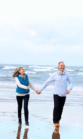 Una pareja de la mano caminando en la playa