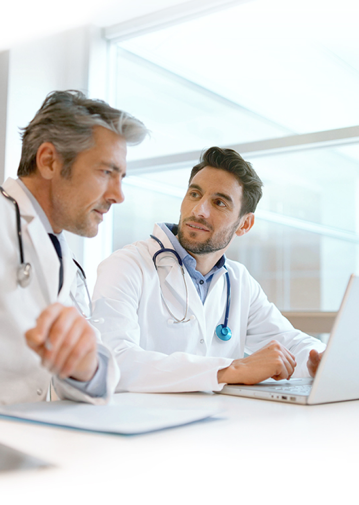 Dos médicos compartiendo una sesión de trabajo frente al computador.