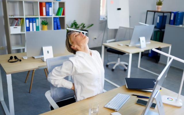 Mujer estirandose en su silla de trabajo 