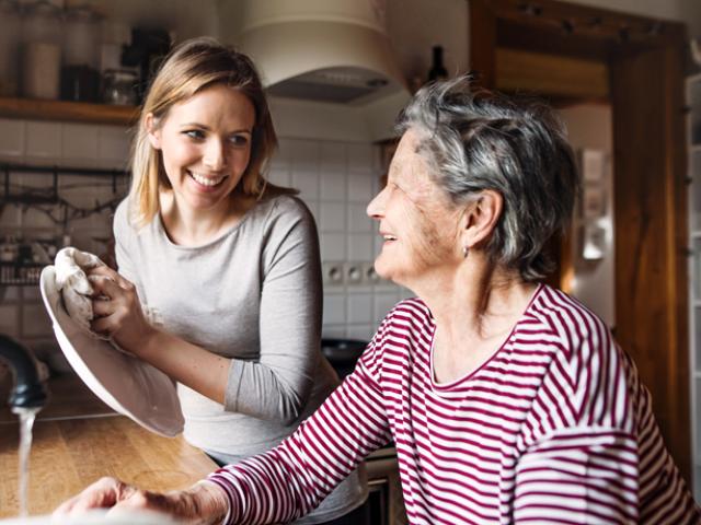 Mujer adulta lavando los platos junto con su mamá